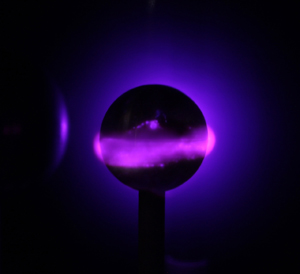 on a dark sphere, a ring of bright purple plasma encircles it.