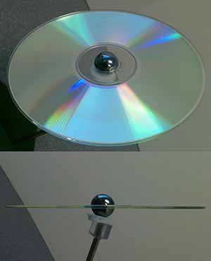 A photo of a CD seen top down with a marble stuck in the center; A photo of the same CD disk and marble seen edge on