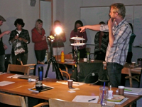 adults standing in a circle around a lit light bulb